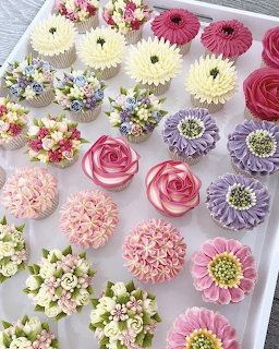 Tray of cupcakes decorated with colorful buttercream flowers in pink, purple, white, and green