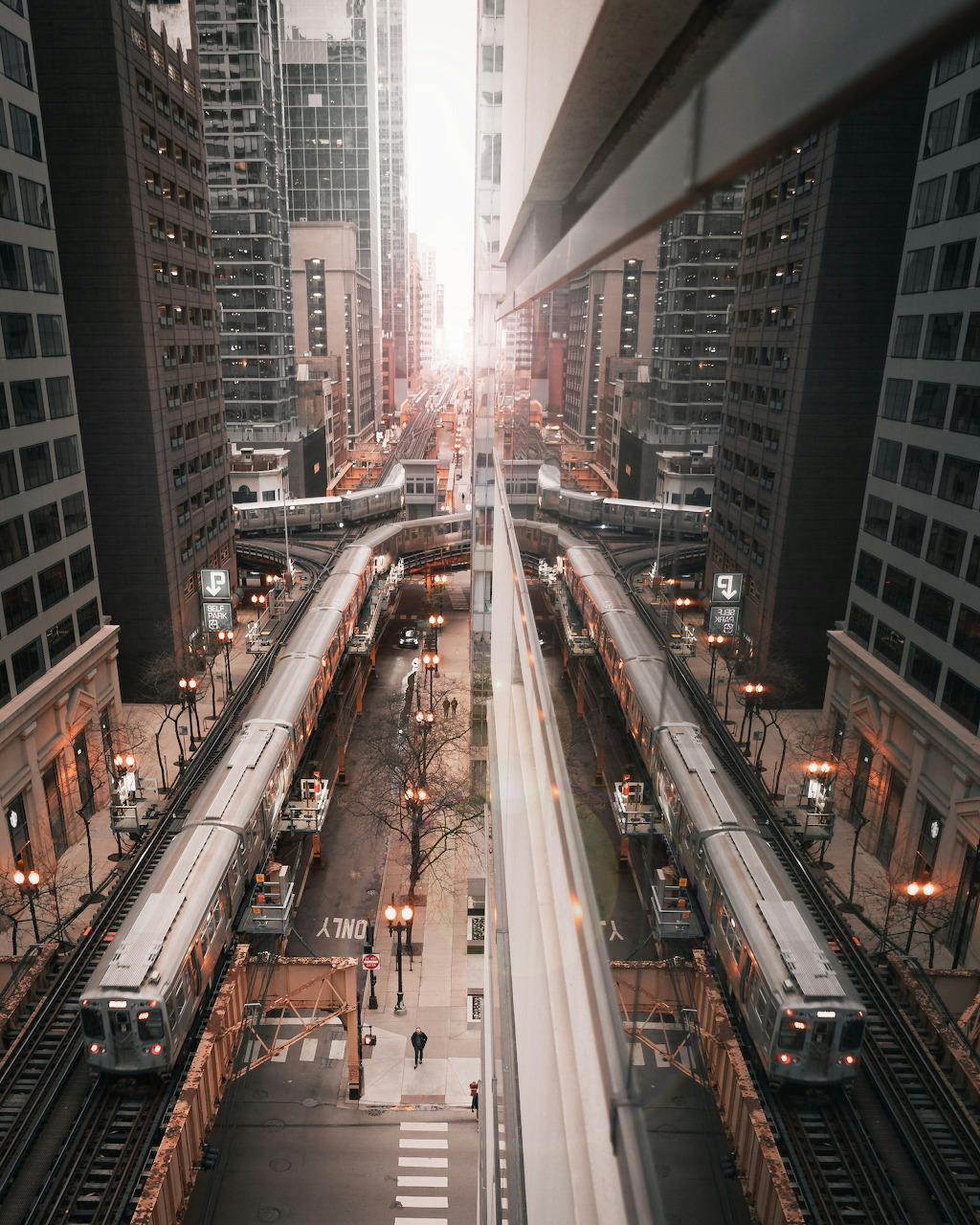 Aerial view of Chicago elevated train tracks between tall city buildings with warm sunset light