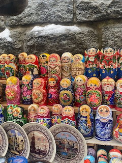 Colorful matryoshka dolls and souvenir plates displayed on shelves by a stone wall