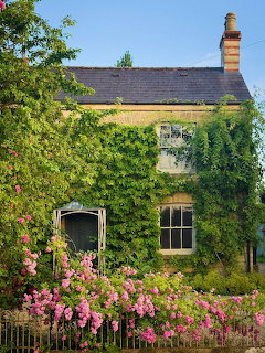 Stone cottage with ivy walls, pink flowering garden, and traditional architecture in the Cotswolds countryside