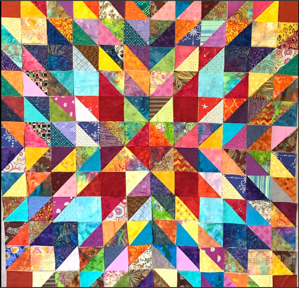 Colorful patchwork quilt with geometric star pattern made of triangular fabric pieces in multiple bright colors