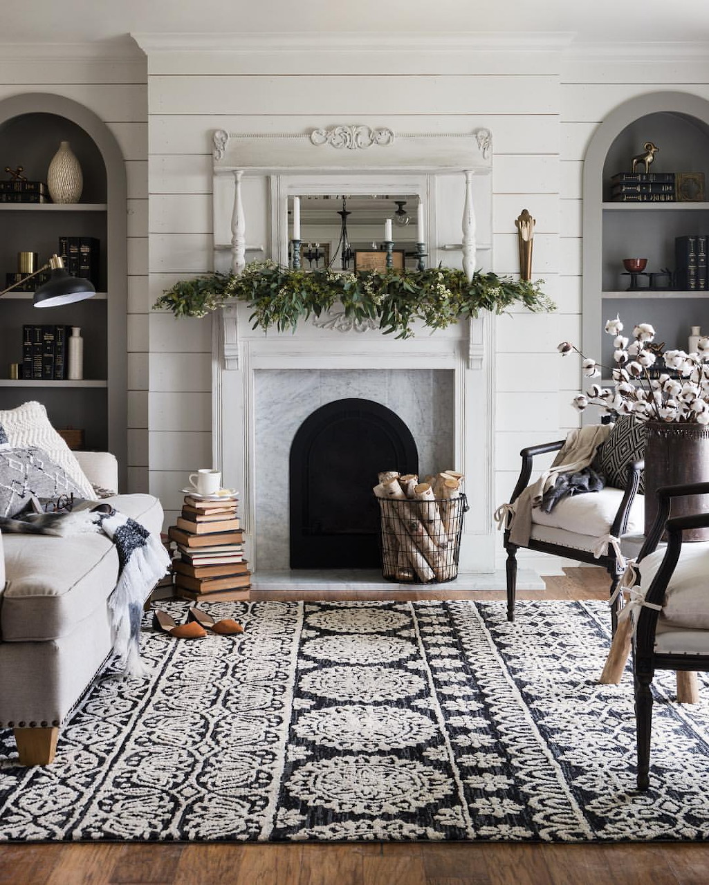 White fireplace with Christmas evergreen garland in elegant living room with built-in bookshelves