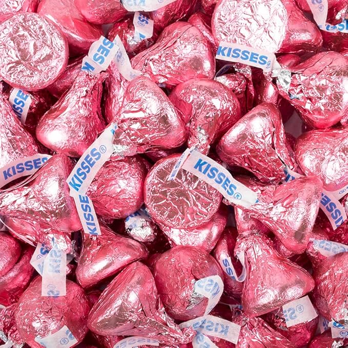 Close-up of pink foil-wrapped chocolate kisses piled together with white paper tags