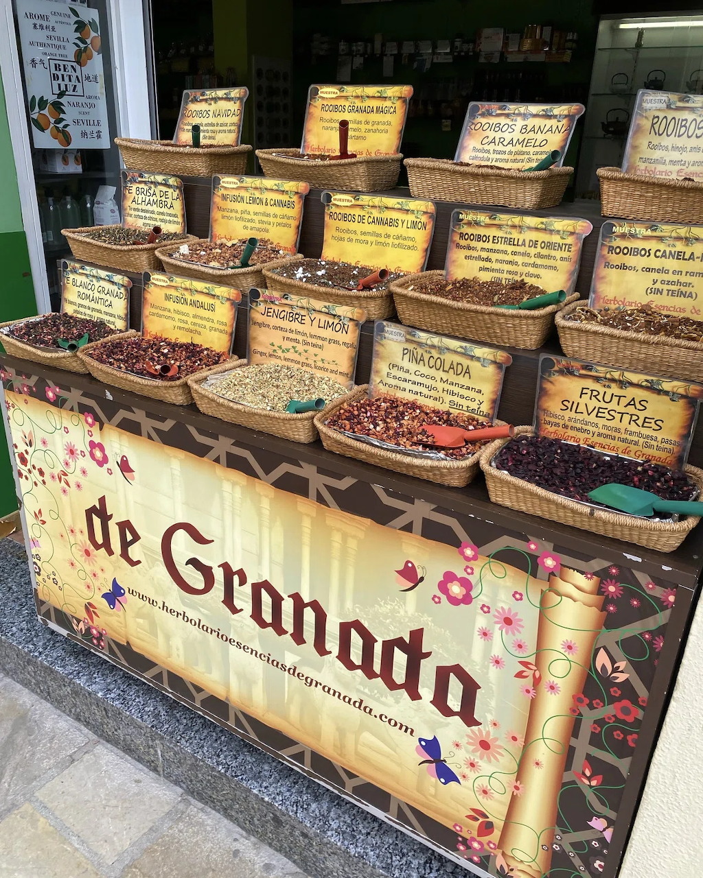 Market stall in Granada, Spain with tiered baskets of dried spices, herbs, and fruits on display