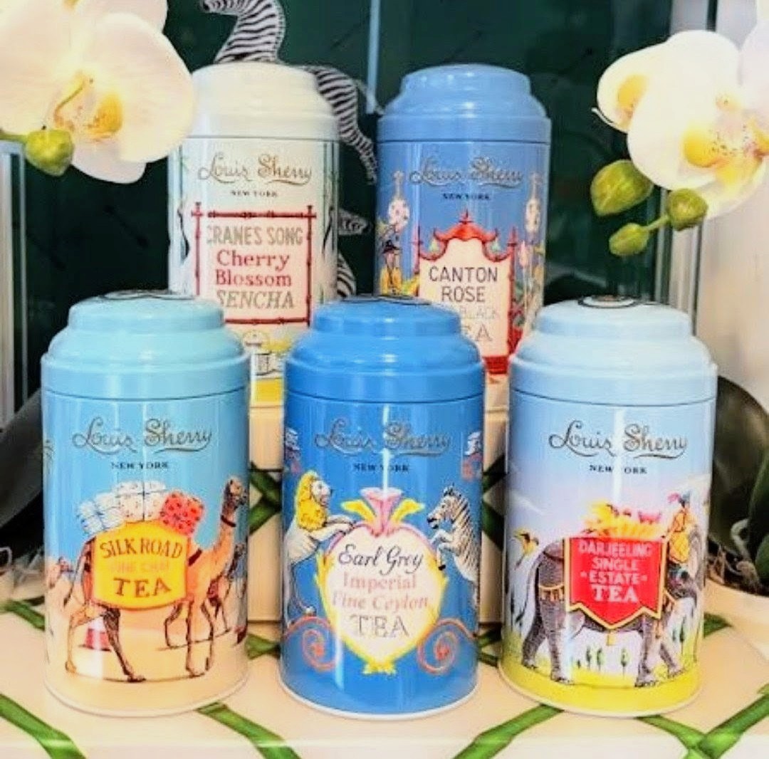 Five pastel tea canisters displayed beside white orchid flowers