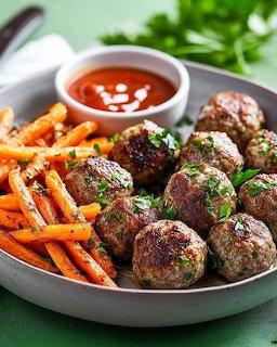 Plate of meatballs with parsley garnish, roasted carrot fries, and red dipping sauce on green surface