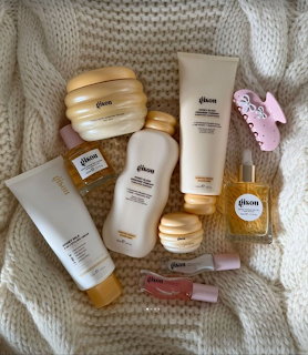 Flat lay of Gisou hair care products on a cream knit blanket with pink hair clips