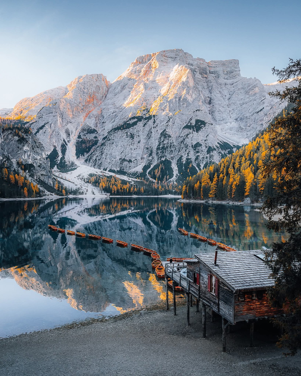 Alpine lake reflecting Dolomite mountain peaks surrounded by pine trees