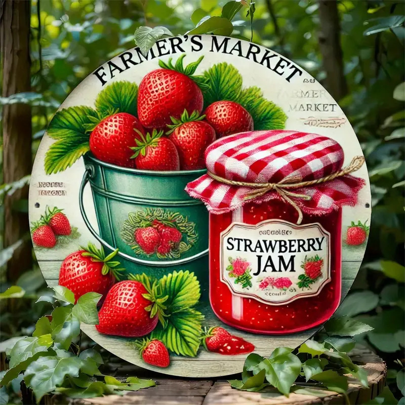 Strawberries in bucket next to jar of strawberry jam with red checkered lid and farmer's market sign