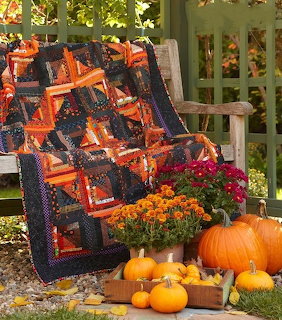 Patchwork quilt on a wooden chair with pumpkins and orange flowers outdoors