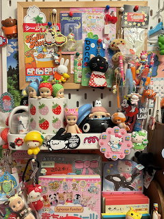 Clutered desk covered with Sonny Angel dolls, Sanrio figurines, stickers, and colorful kawaii collectibles