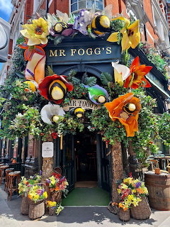 Flower-covered entrance to Mr Fogg's with colorful floral decorations and greenery on a city street.