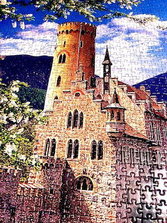Medieval castle with tall red tower, Gothic windows, church spire, mountains and blue sky background