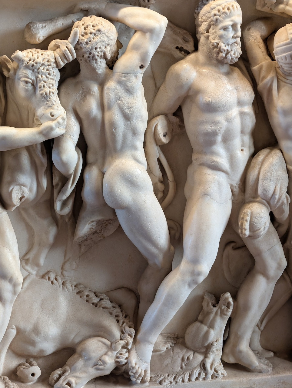 White marble relief sculpture showing muscular classical mythological figures including Hercules