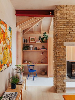 Warm interior with brick fireplace wall, abstract painting, and small desk nook