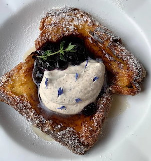 French toast with cream and dark berries on a white plate