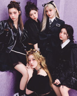Five young women in dark outfits posing together in a mody purple-lit studio setting