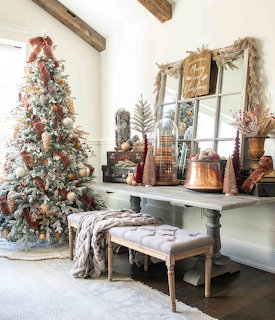 White flocked Christmas tree with copper decorations in rustic farmhouse living room with wooden beams and vintage decor