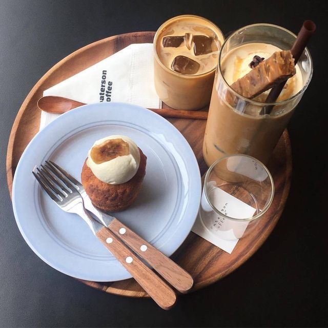Overhead view of iced coffee drinks and a cupcake on a wooden tray