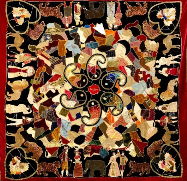 Ornate Victorian crazy quilt with embroidered floral center, patchwork pieces, and decorative corners