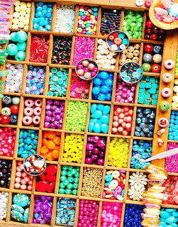 Wooden box with many compartments filled with colorful beads in various shapes and sizes