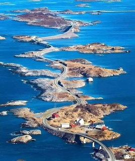 Aerial view of winding coastal road with bridges connecting small rocky islands over bright blue ocean water