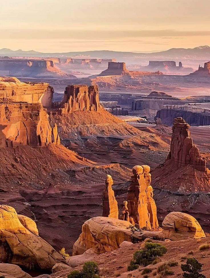 Golden hour view of red sandstone mesas and rock spires in a vast desert canyon landscape
