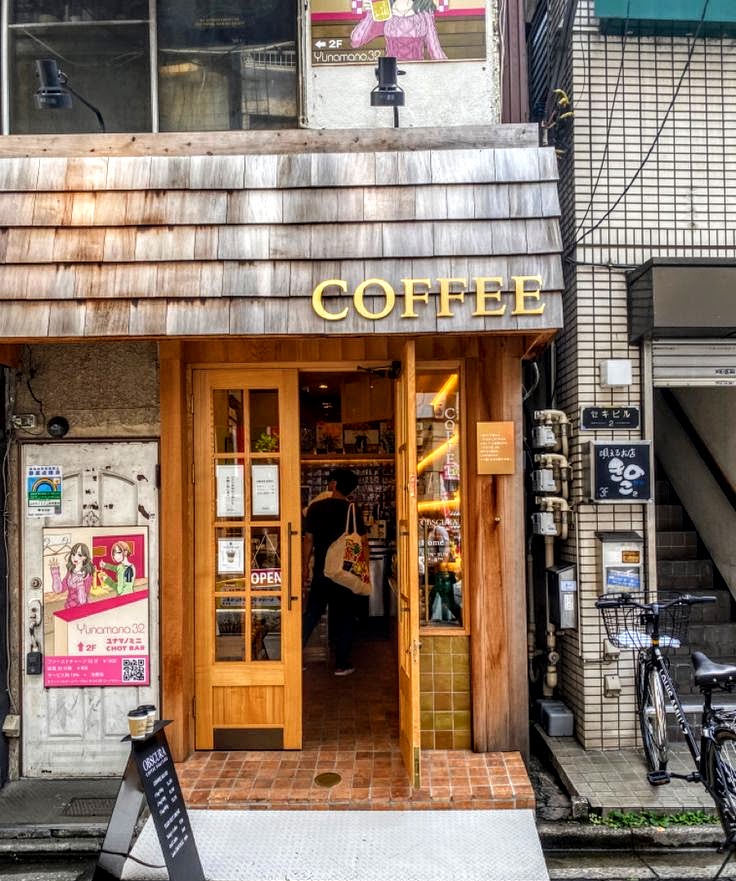 Exterior of a Japanese coffee shop with wooden entrance doors and a lit COFFEE sign above
