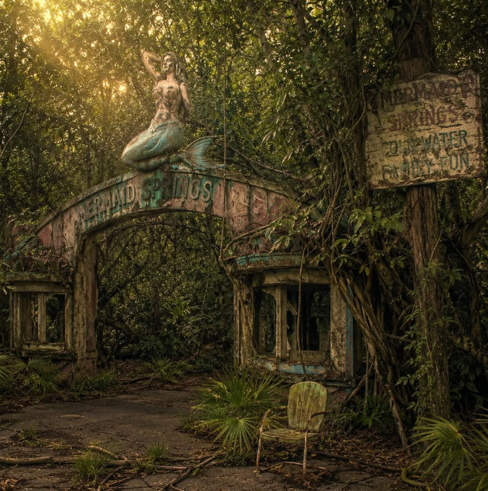 Mermaid statue on ivy-covered abandoned cottage with wooden signs in enchanted forest