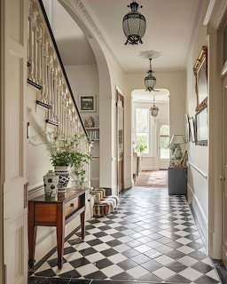 Elegant hallway with black and white checkered floor, staircase, arched ceiling, and antique furniture