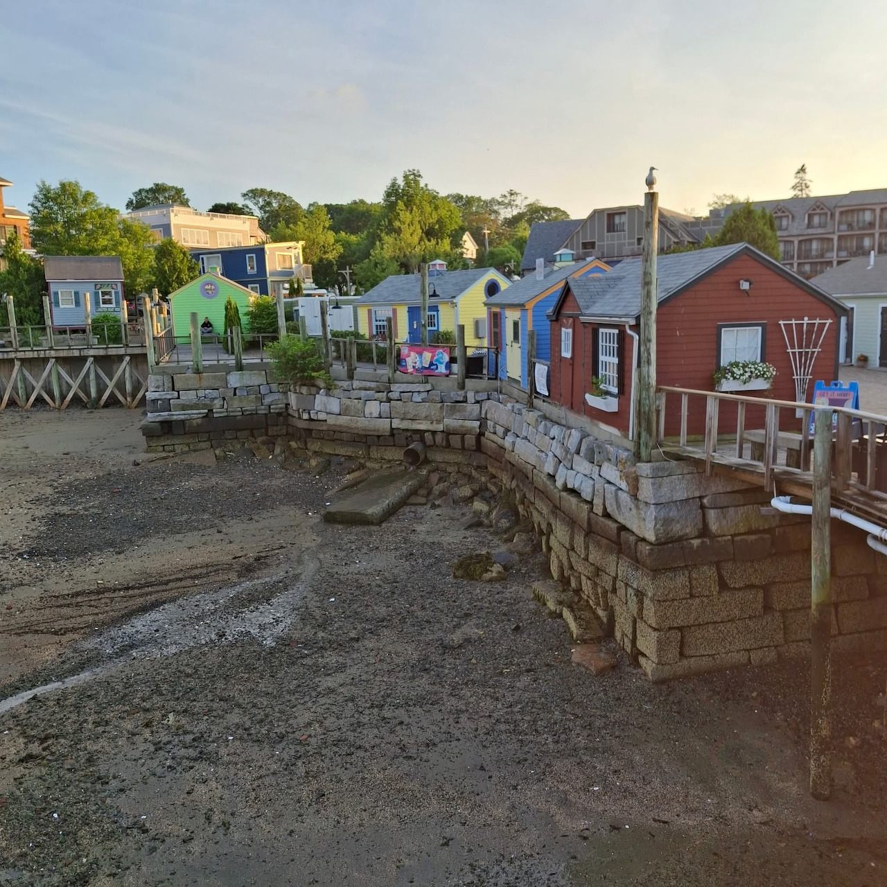 Colorful small buildings along a stone quay by a muddy harbor at low tide