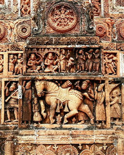 Intricate sandstone relief carvings on an Indian temple showing horses, figures, and floral patterns