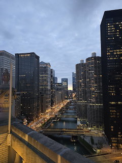 Chicago River flanked by tall illuminated buildings at dusk with bridges crossing the waterway