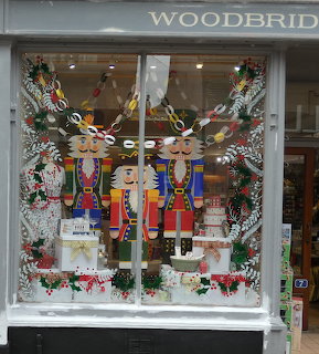 Christmas shop window with two colorful nutcracker soldiers, decorated trees, presents, and festive garlands