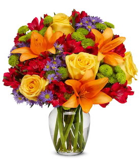 Colorful bouquet with roses, lilies, and assorted flowers in clear glass vase