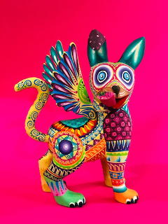 Colorful alebrije animal sculpture with detailed patterns on a bright pink background