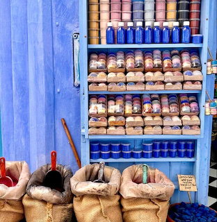 Colorful spice jars and open sacks displayed in a bright blue market stall