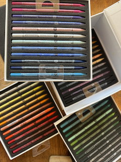Multiple boxes of colored pencils sorted by color on wooden table