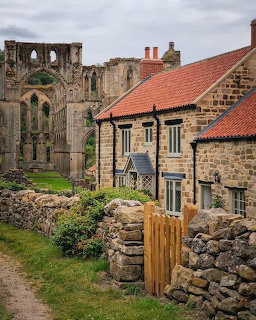Stone cottages and walls with Rievaulx Abbey ruins in the background