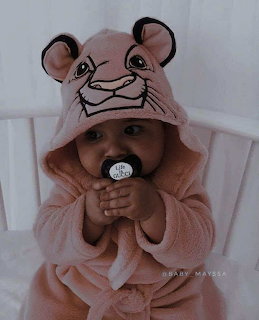 Baby in pink mouse-eared hooded bathrobe with pacifier in white crib