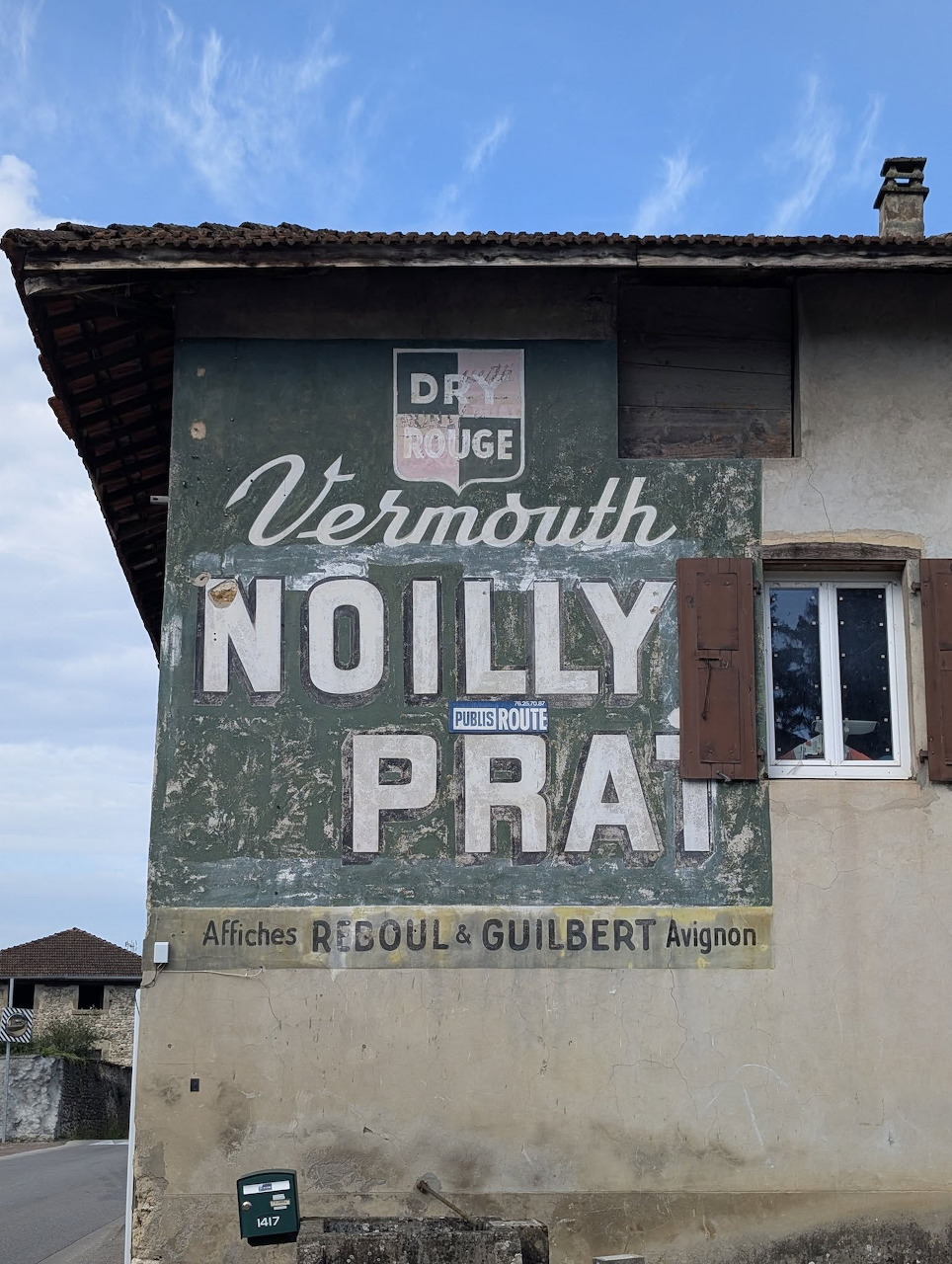 Vintage painted wall advertisement for Noilly Prat vermouth on the side of a French building