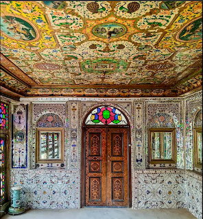 Ornate palace interior with painted ceiling, carved wooden door, and stained glass windows