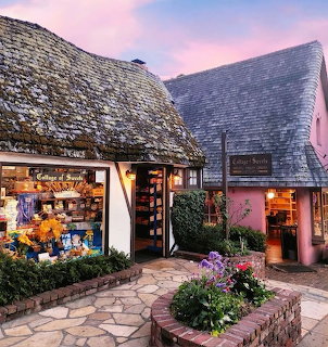 Quaint cottage-style shops with slate roofs and flower displays in Carmel village at sunset