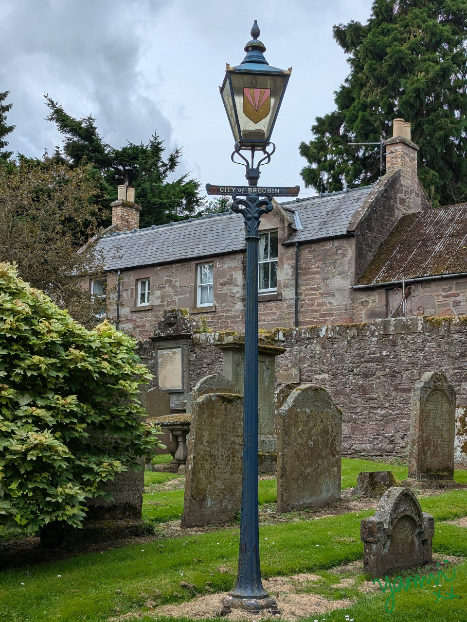 Old churchyard with gravestones and vintage street lamp in front of stone building