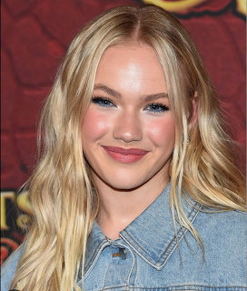 Smiling blonde woman in denim shirt against red backdrop