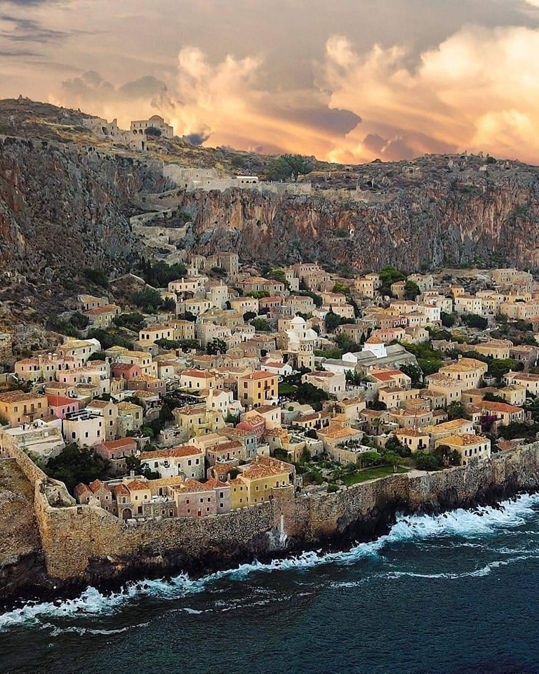 Cliffside stone village of Monemvasia beside the sea under a dramatic sunset sky
