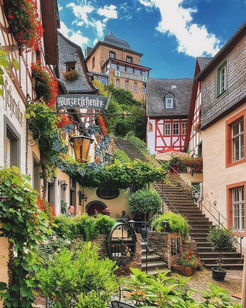 Colorful half-timbered buildings with greenery and stone stairs in Cochem, Germany