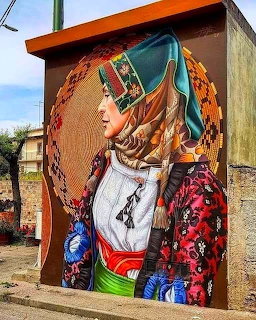 Large street mural of a woman in traditional clothing painted on a building wall