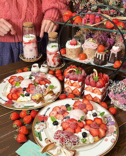 Tiered dessert display with strawberry cakes, tarts, and pastries on decorative plates