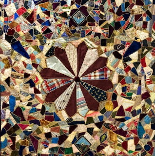 Colorful crazy quilt with central starburst pattern and irregular patchwork pieces with embroidered embellishments